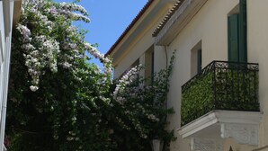 A building with a balcony, a clear blue sky, and flowering trees. - Athenian House in Plaka (Athens)