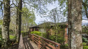 Un sentier en bois mène à un bâtiment entouré d’arbres.