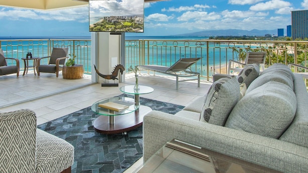 A modern balcony with a glass table, wicker chairs, and a sofa. - A View to Die for! 3 bedroom 3 bath on the sand at Waikiki Beach (Honolulu)
