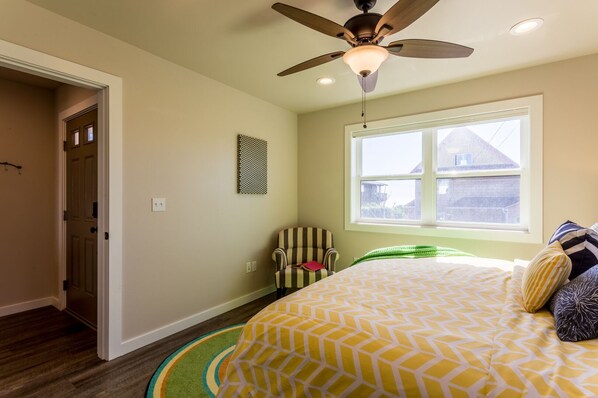 A bedroom with a bed, a ceiling fan, a window, and a door. - Nye Beach, Hot tub, Dog friendly, Hip Decor, Walk to Beach! (Newport)