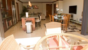 A modern kitchen with stainless steel appliances, a central island, and a dining area with wicker furniture.