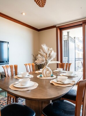 A dining area with a round table, chairs, and a vase with dried plants.