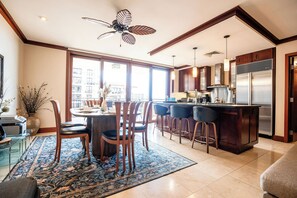 A modern kitchen with a central island, bar stools, and a large refrigerator. - Luxury Ko Olina Beach Villas: Panoramic Ocean View 3BR (Kapolei)