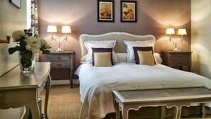 A neatly arranged hotel room with a large bed, two bedside tables with lamps, a small table with a vase of flowers, and a wall with two framed pictures. - Eiffel-Invalides, New & Elegant  (Paris)