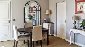 A dining area with a table, chairs, a mirror, and a lamp. - Eiffel-Invalides, New & Elegant  (Paris)