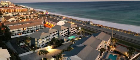 Un hotel costero con varias edificaciones, piscina y vista a la playa.