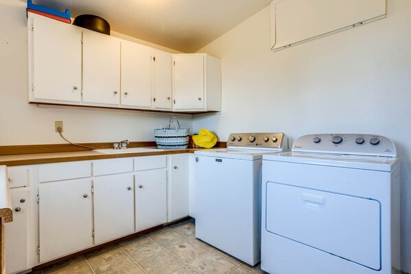A compact kitchen with white cabinets, a countertop, a stove, and a washing machine.