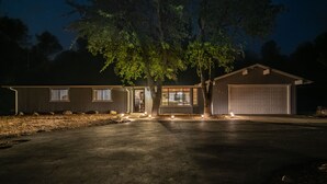 Ein Wohnhaus mit Garage, Auffahrt und einer gut beleuchteten Einfahrt bei Nacht.