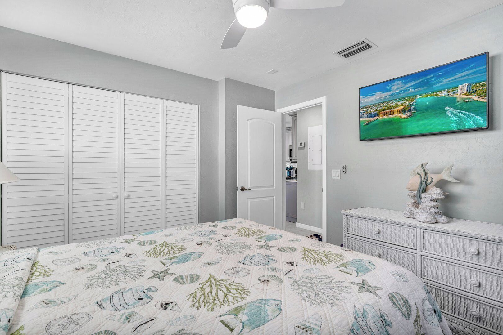 Ein Schlafzimmer mit Bett, Kleiderschrank, Kommode, einem Gemälde und einem Deckenventilator.