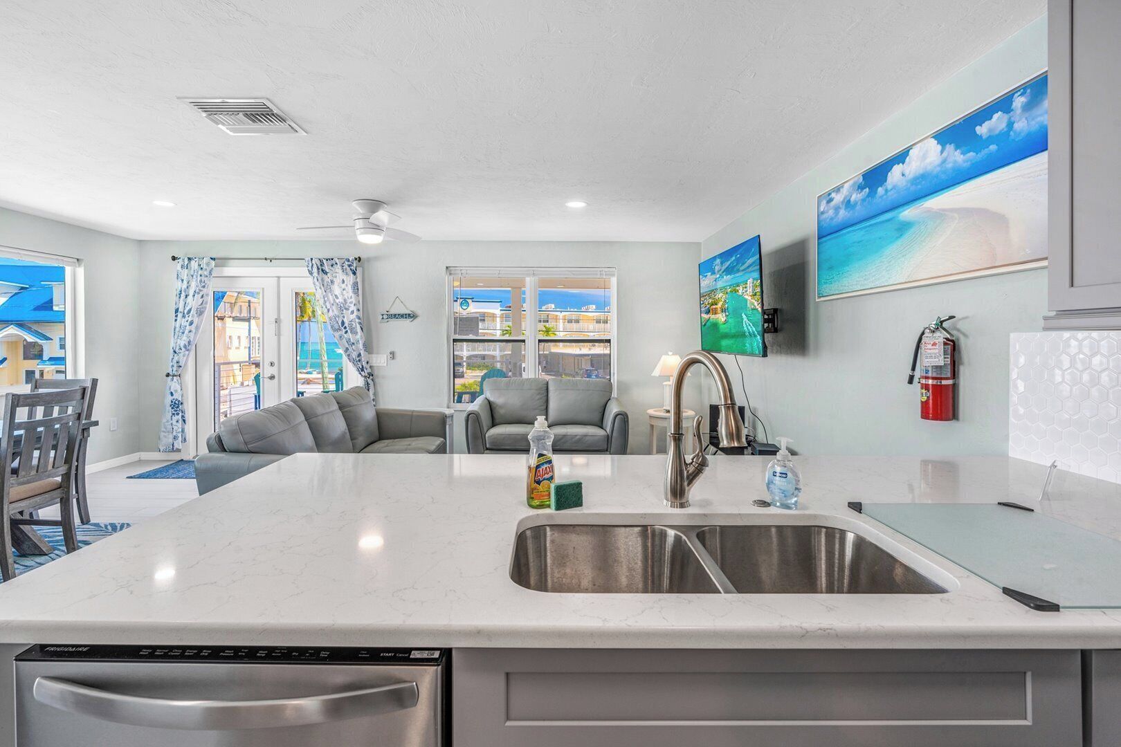 A modern kitchen with a large island, stainless steel appliances, and a view of the sea through the windows.
