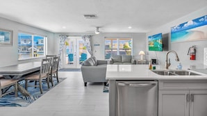 Une cuisine moderne dotée d’un îlot central, d’un coin repas avec des chaises et d’un salon avec un canapé.