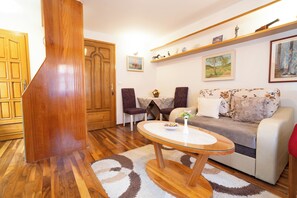 A living room with a wooden staircase, a round glass table, a sofa, and a coffee table. - Studios Belvi (Kotor)