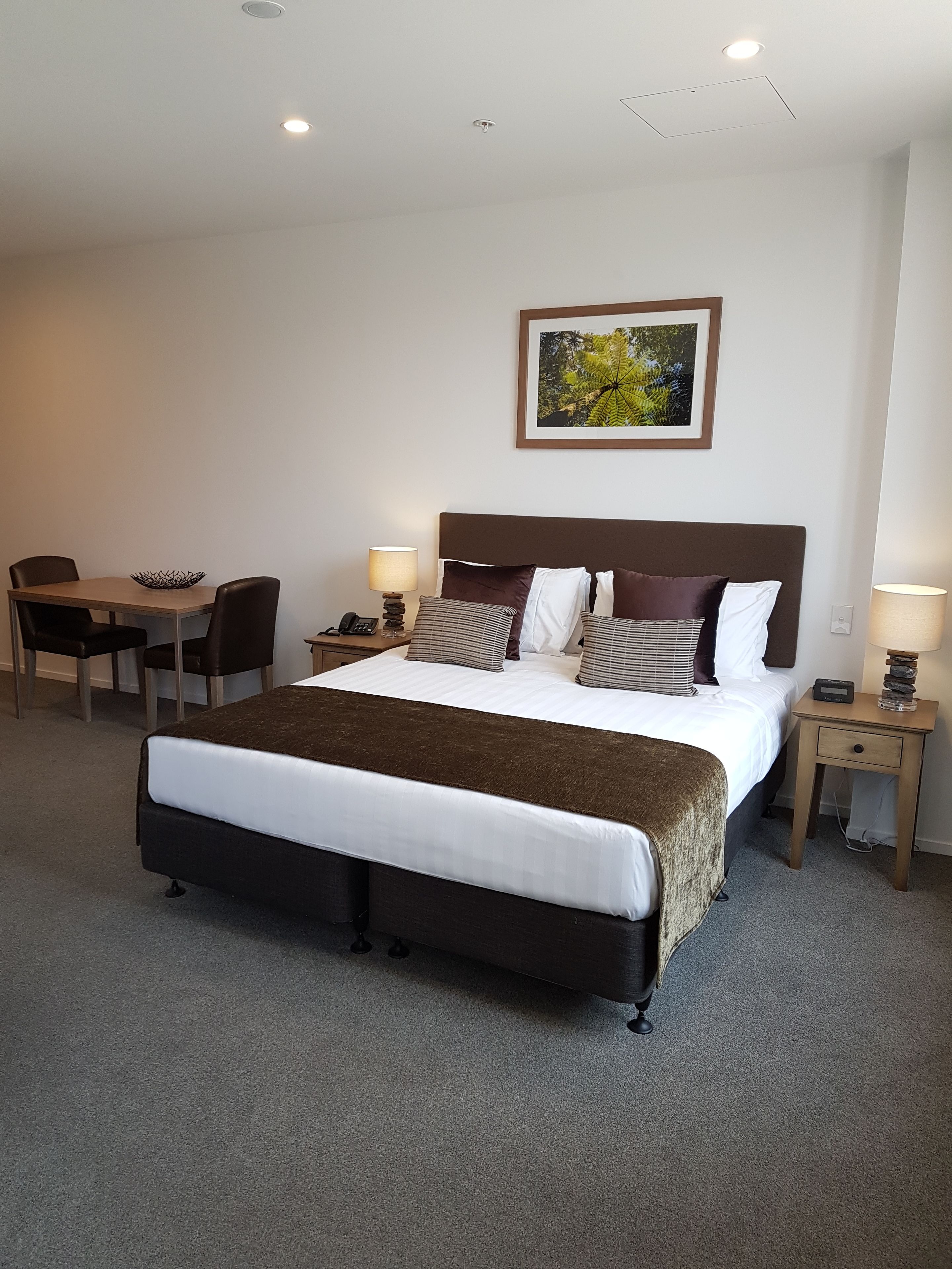 Une chambre d’hôtel avec un grand lit, des tables de chevet, un bureau et une chaise.