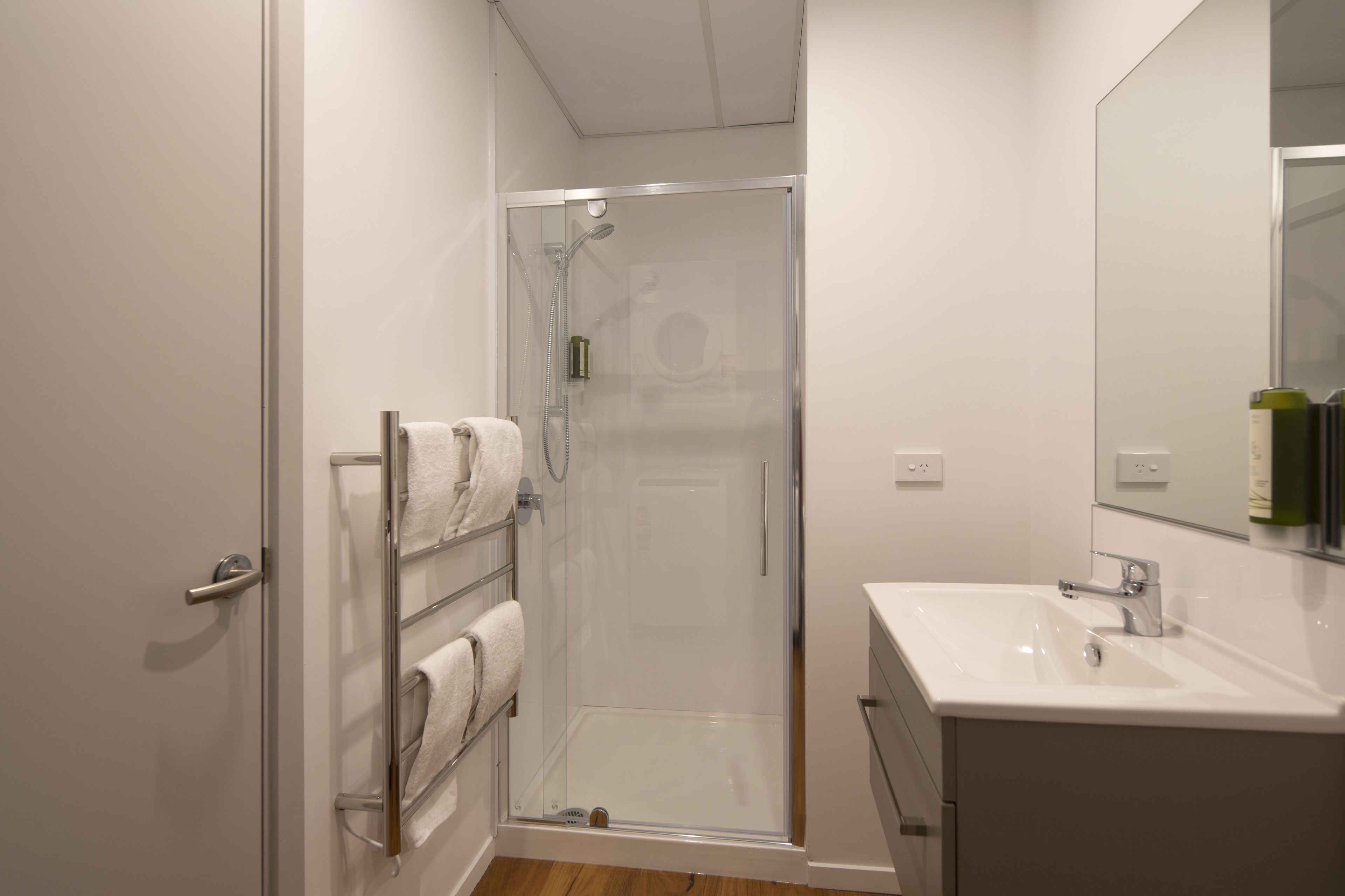 Une salle de bain moderne avec une douche à parois de verre, un lavabo blanc et un porte-serviettes.