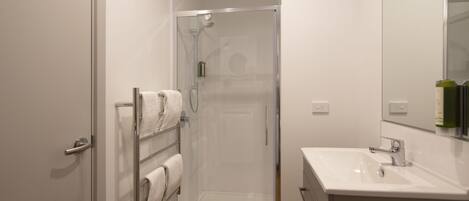 A modern bathroom with a glass-enclosed shower, a white sink, and a towel rack.