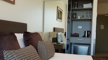 Una habitación de hotel con cama, almohadas, un escritorio y un espejo.