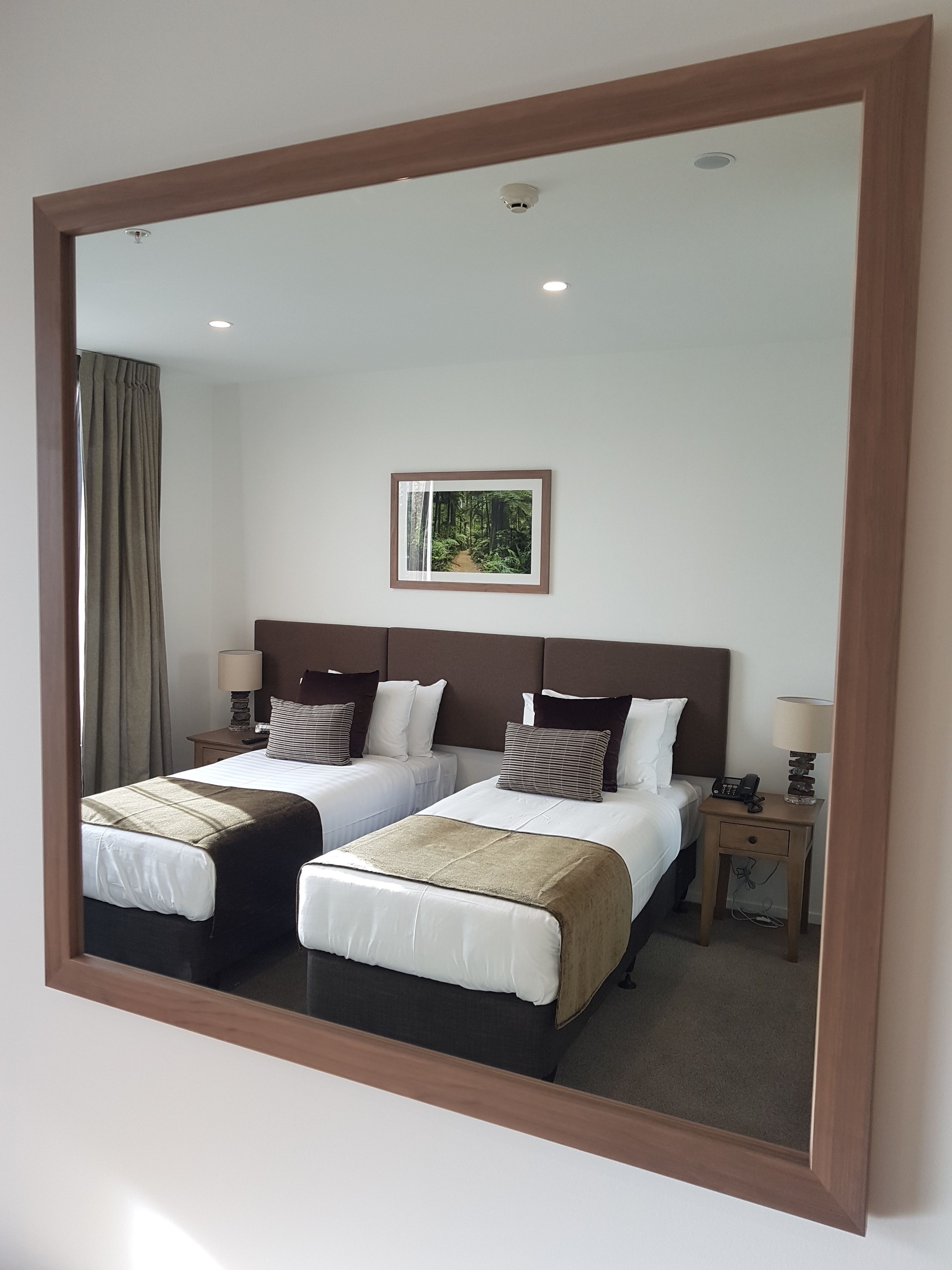 Habitación de hotel con dos camas, una mesita de noche con teléfono, lámpara y un cuadro en la pared.