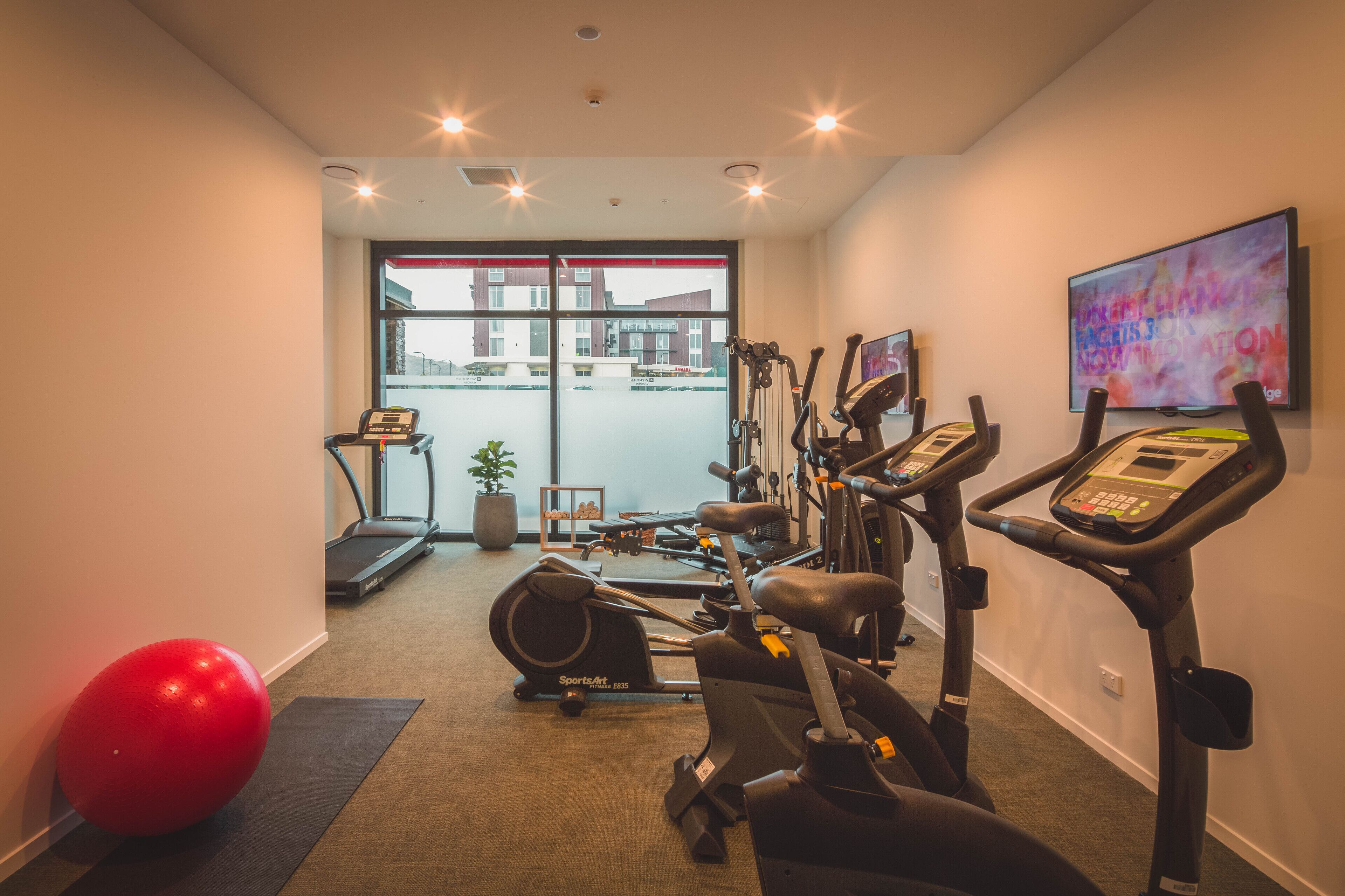 A gym with exercise equipment, a treadmill, and a large window.