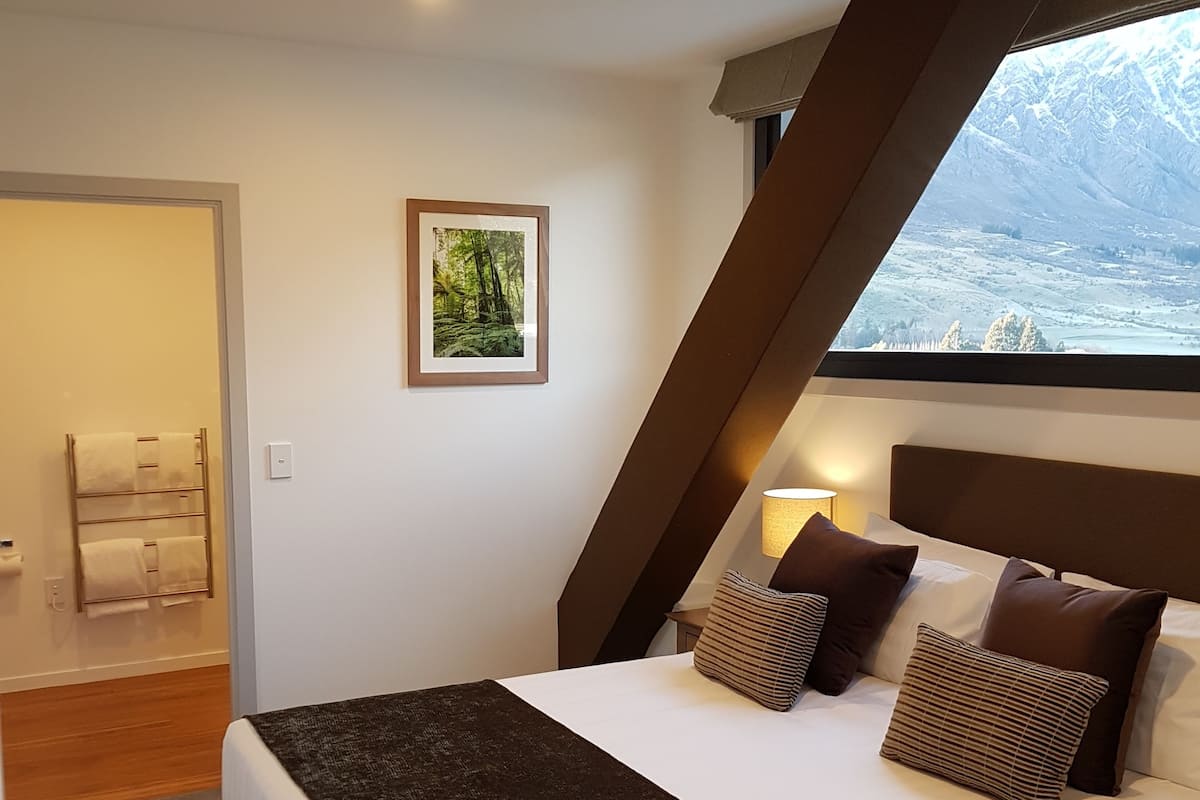 A modern bedroom with a large bed, a view of a snowy landscape, and a framed picture on the wall.