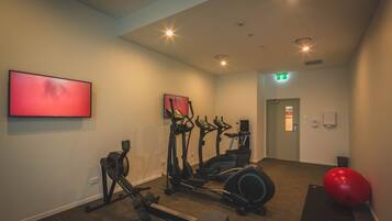 A gym with cardio equipment, a red exercise ball, and a treadmill.