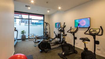 Ein Fitnessraum mit Cardiogeräten, einem Rudergerät und einem roten Trainingsball.