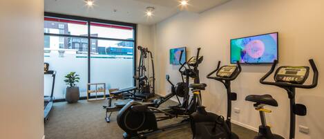 A gym with cardio machines, a rowing machine, and a red exercise ball.