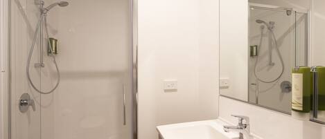 Une salle de bain avec une douche à parois de verre, un lavabo blanc et un miroir au-dessus du lavabo.
