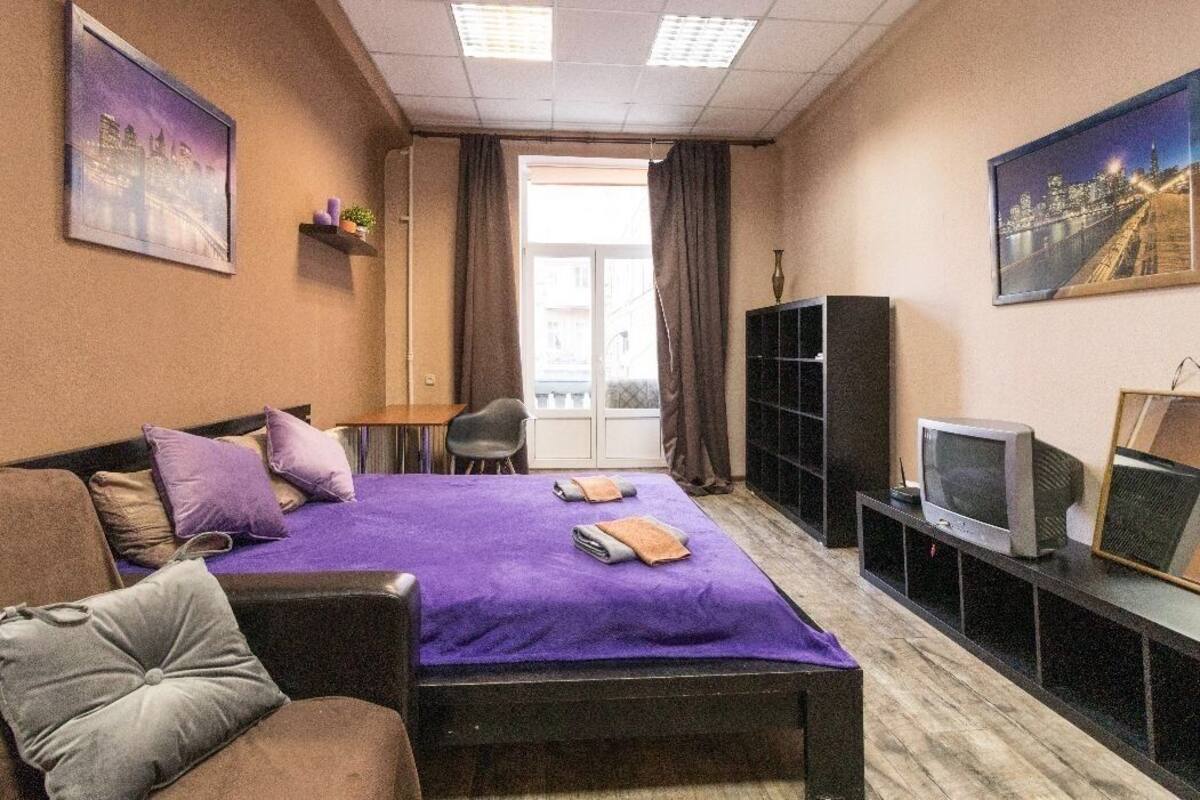 A compact hotel room with a single bed, a sofa, a television, and a small desk.