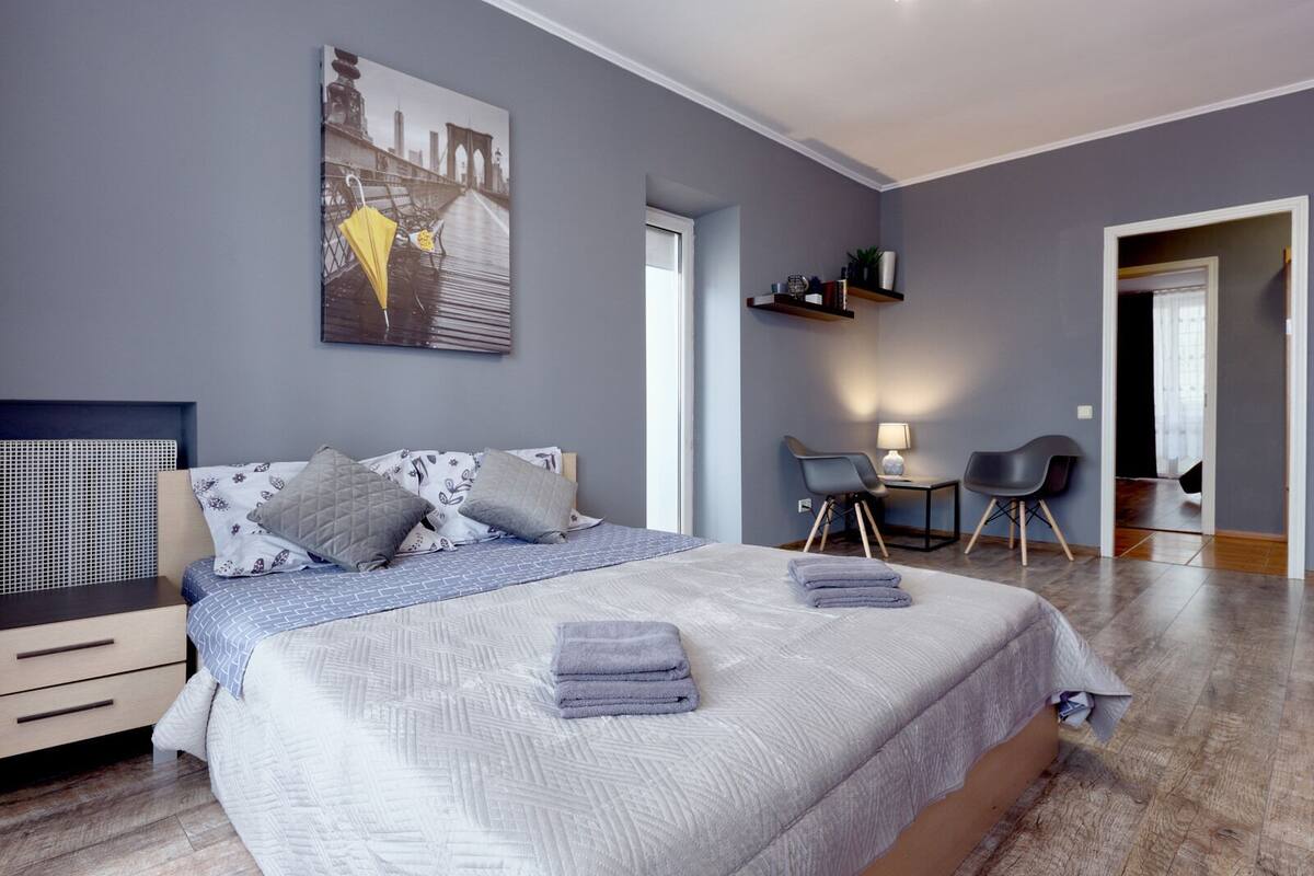 A modern bedroom with a large bed, a desk, and a chair.