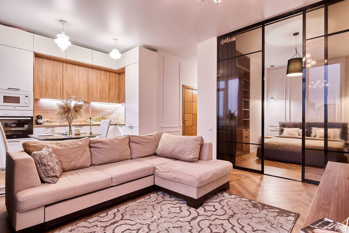 A modern living room with a sectional sofa, a dining area, and a kitchen.