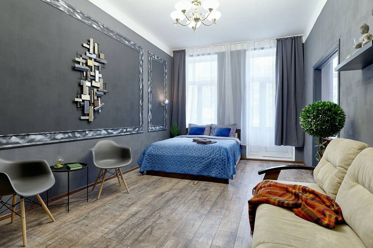 A modern bedroom with a large bed, a sofa, a chair, and a small table.