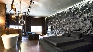 Quarto moderno com uma cama grande, parede de pedra decorativa e piso de madeira.