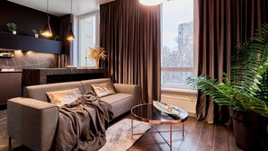 Uma sala de estar moderna com sofá, mesa de centro e uma grande janela com cortinas.