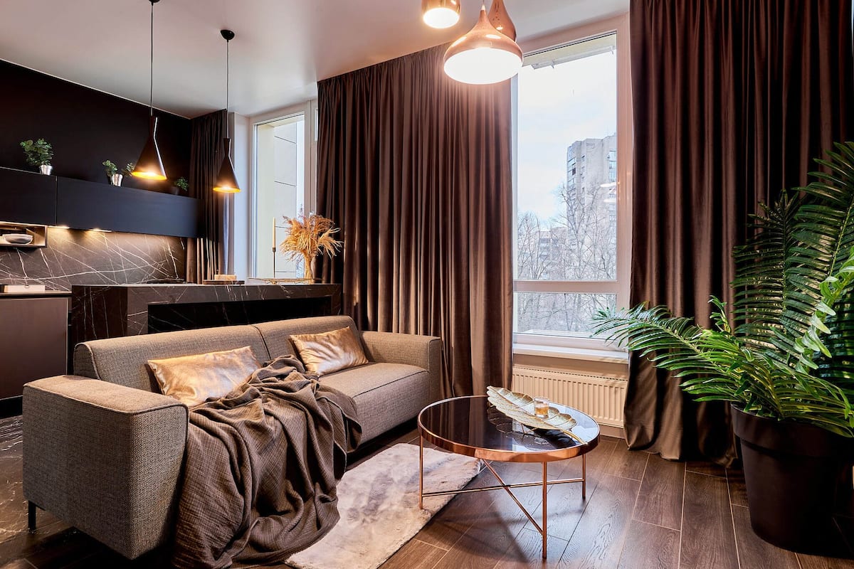 A modern living room with a sofa, a coffee table, and a large window with curtains.