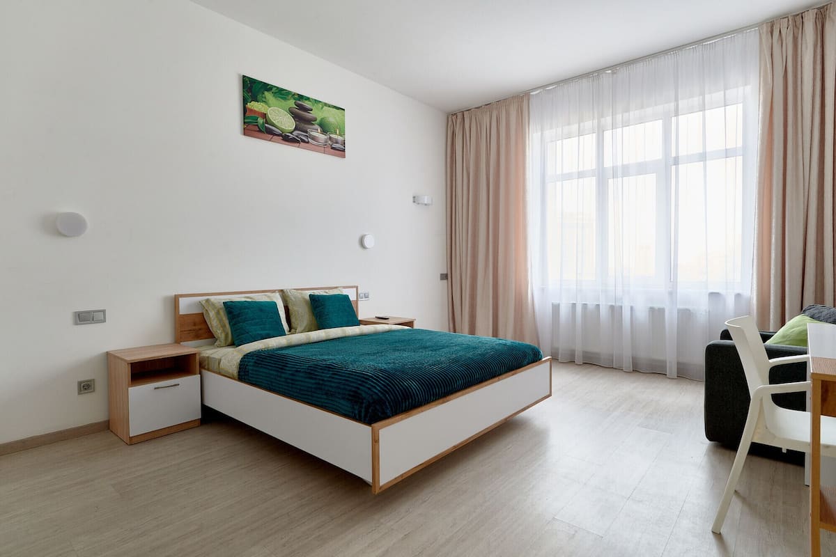 A modern bedroom with a bed, bedside tables, a desk, and a chair.
