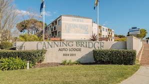 Un motel chiamato 'Canning Bridge Auto Lodge' con un cartello che mostra il nome e il numero di telefono.