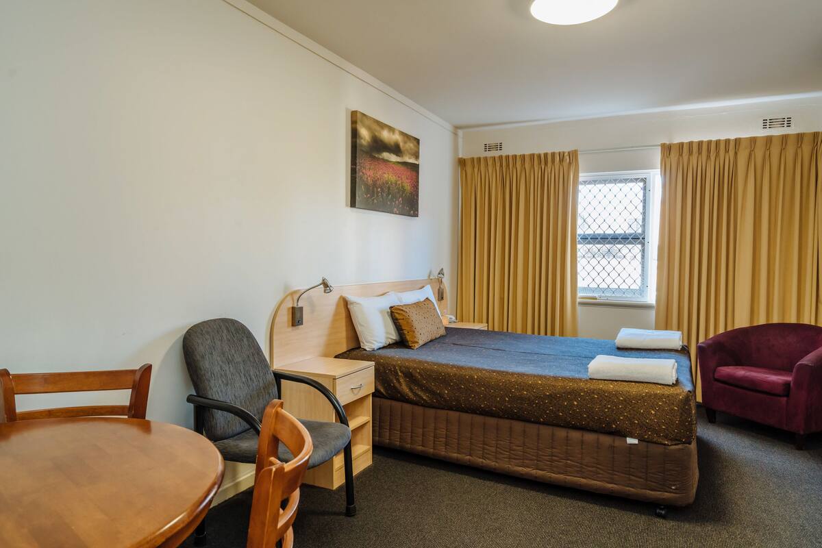 Ein Hotelzimmer mit Bett, Schreibtisch, Stuhl und Esstisch.