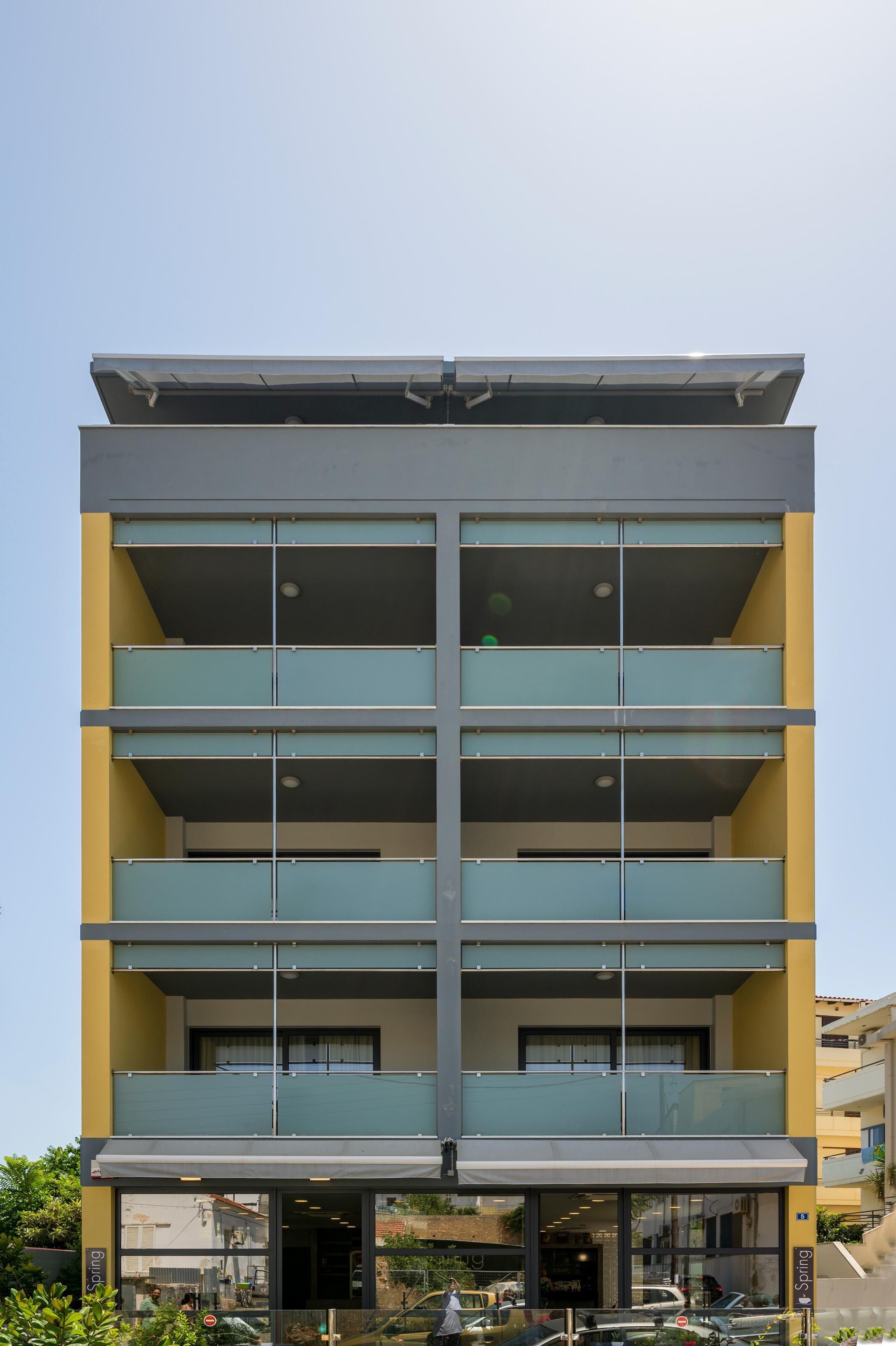 A multi-story building with a modern architectural design, featuring balconies and large windows.