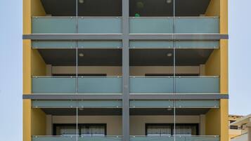 A multi-story building with a modern architectural design, featuring balconies and large windows.