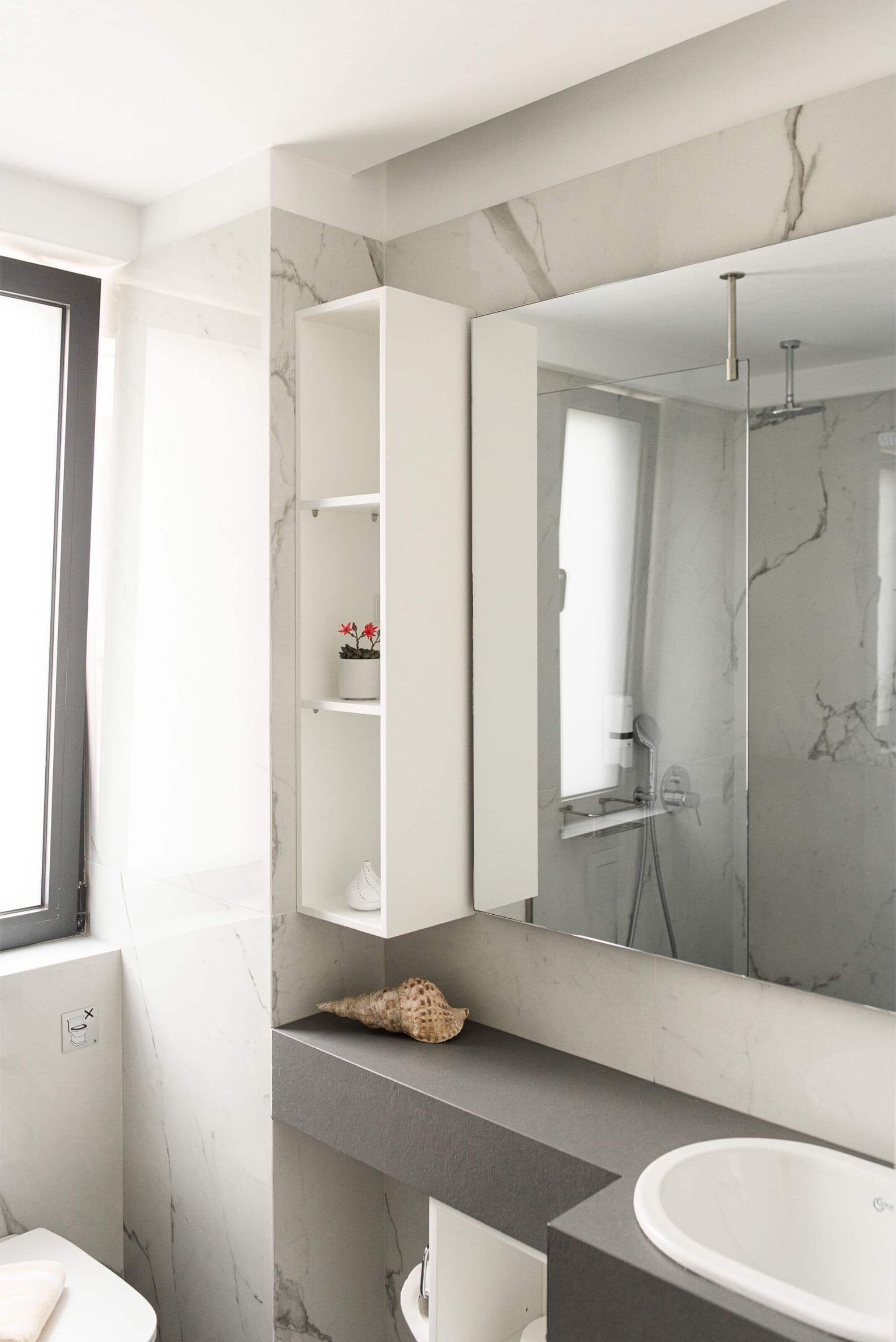 Un baño moderno con tocador de mármol, un espejo grande y cabina de ducha.