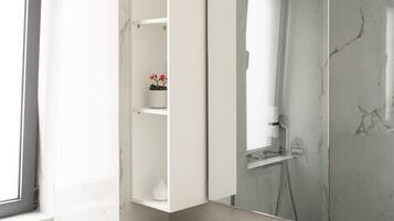 Un baño moderno con tocador de mármol, un espejo grande y cabina de ducha.