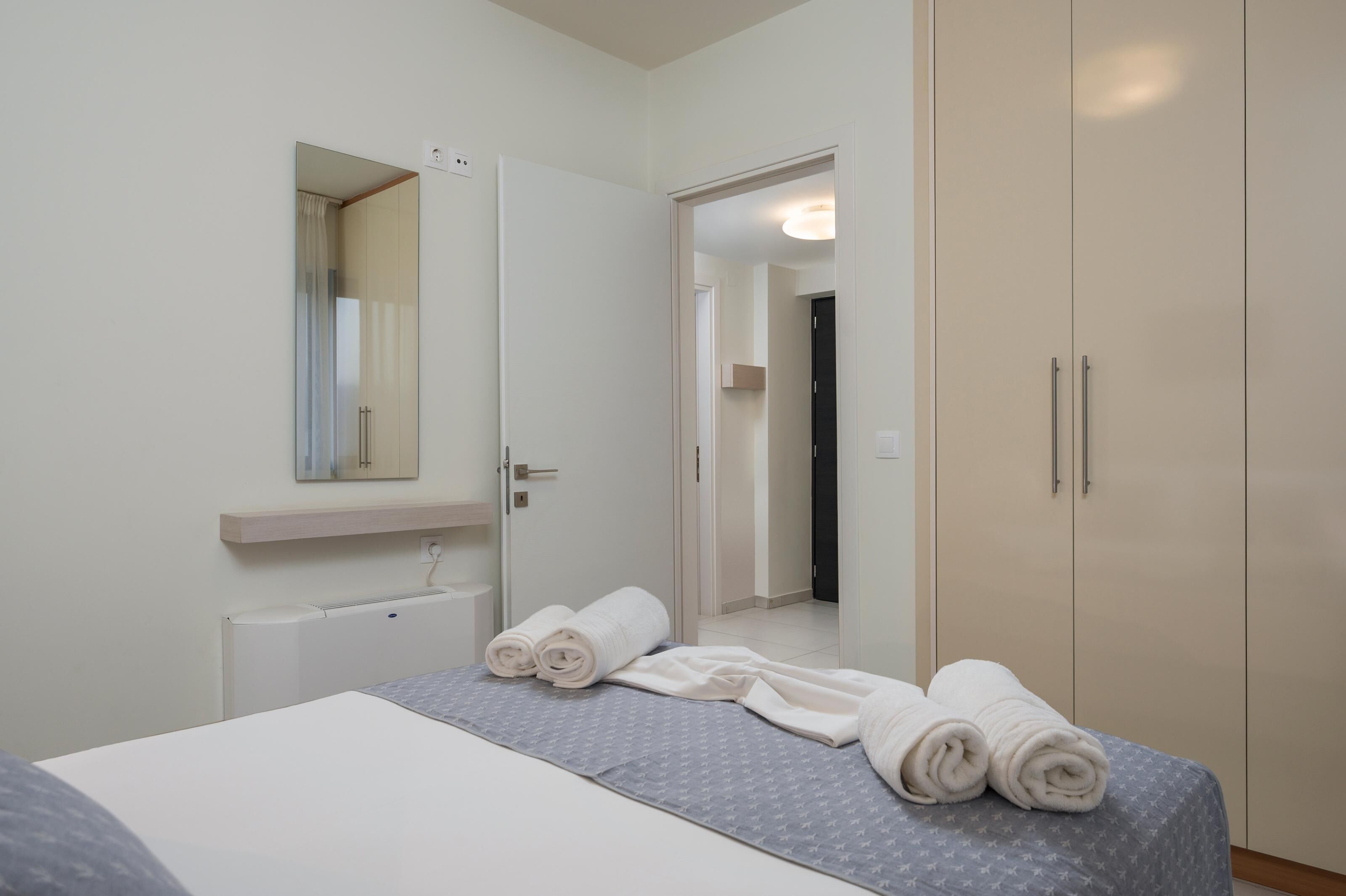 A hotel room with a bed, a mirror, a wardrobe, and a radiator.