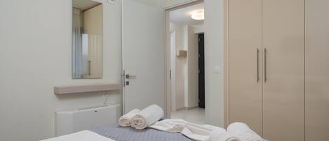 A hotel room with a bed, a mirror, a wardrobe, and a radiator.