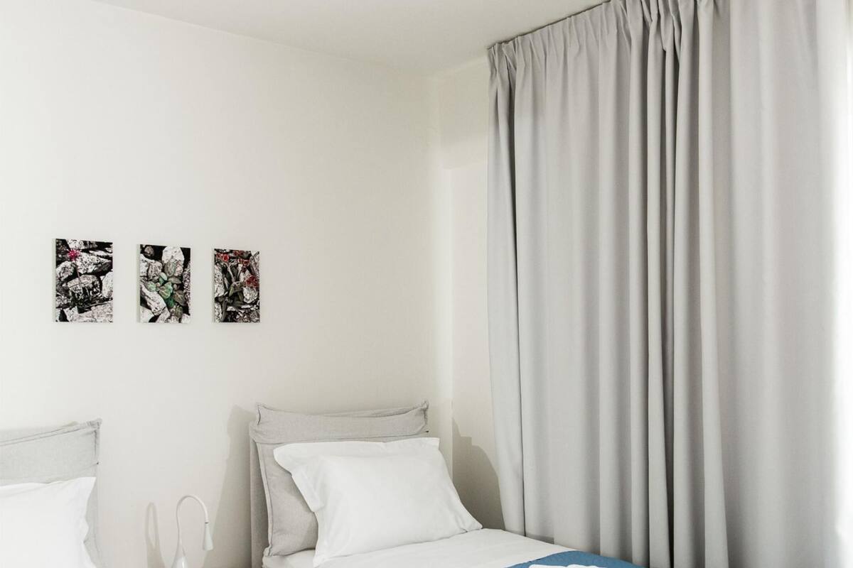 A hotel room with two beds, a ceiling light, and a window with curtains.