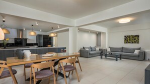 A modern living space with a dining area, a sofa set, and a kitchen in the background. - Spring Apartments (Chania)