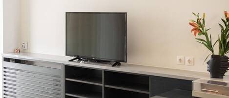 Eine moderne Küche mit einer großen Kochinsel, einem Flachbildfernseher und Pendelleuchten.