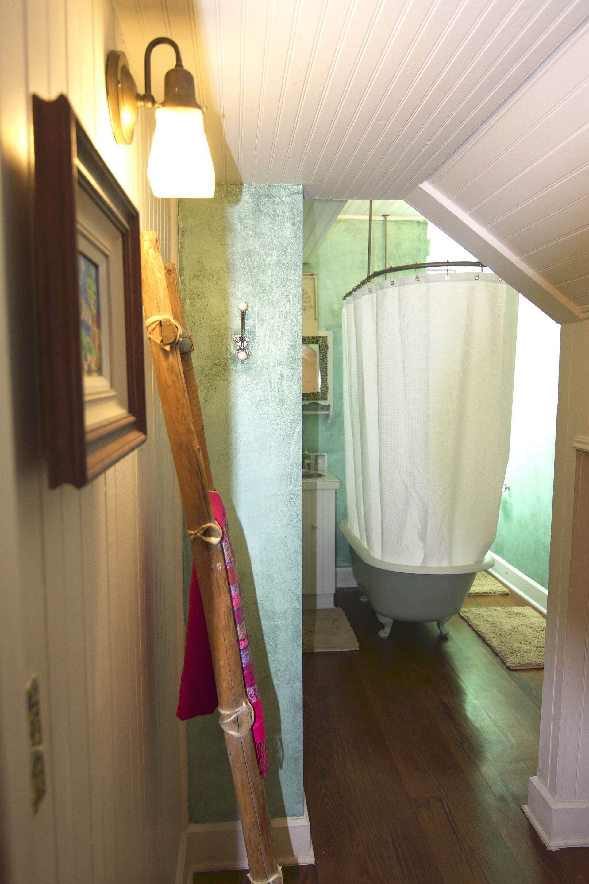 A bathroom with a bathtub, a wooden ladder, and a light fixture.