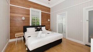 Ein Schlafzimmer mit einem großen Bett, Holzwandverkleidung, einem Fenster mit Blick und einer Tür zu einem Badezimmer.
