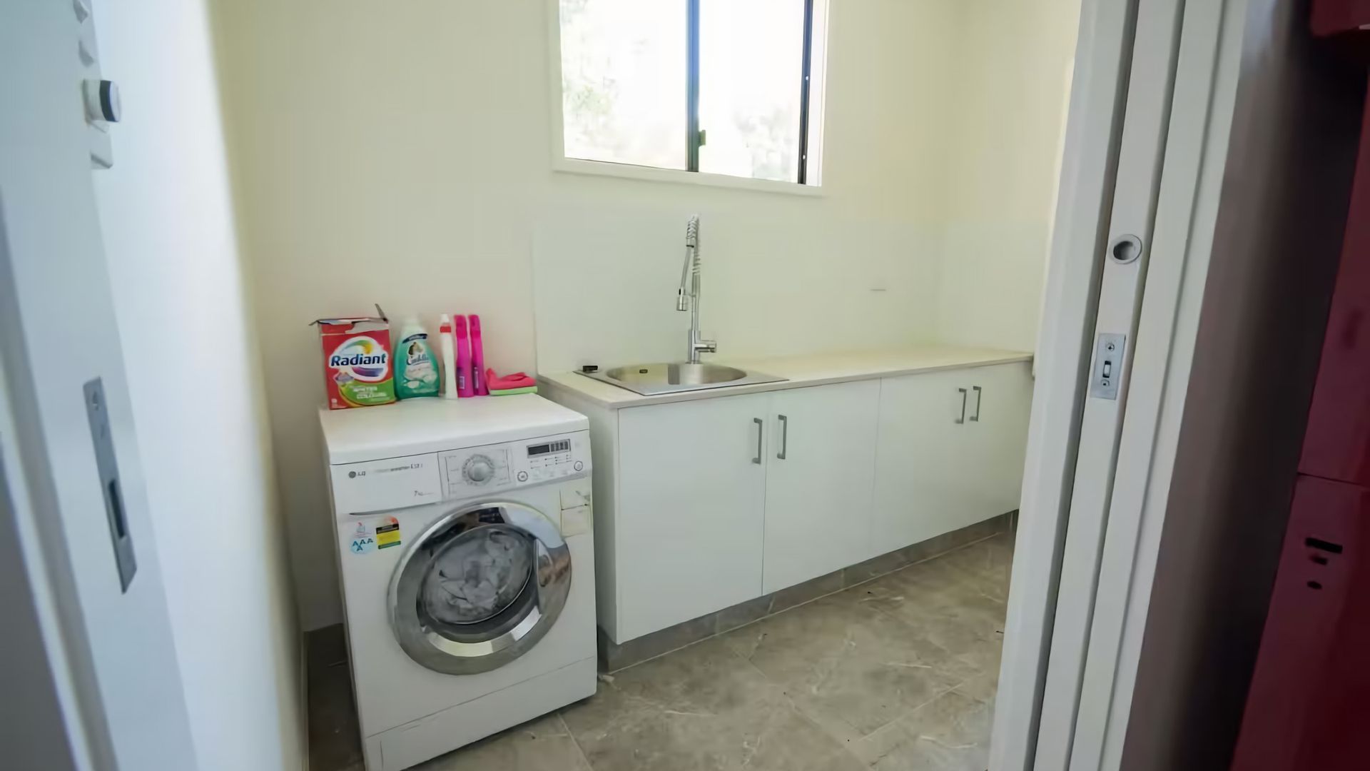 Een wasserette met een wasmachine, een wasbak en kastjes.