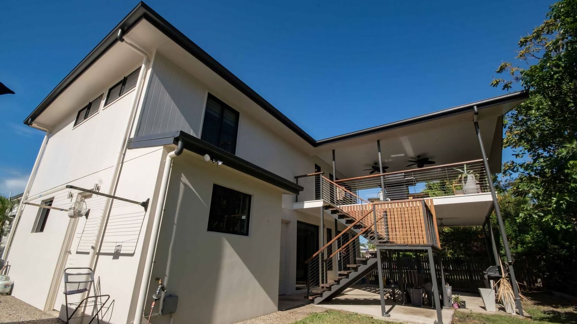Ein zweistöckiges Haus mit Balkon, Treppe und einem sichtbaren Außenbereich.